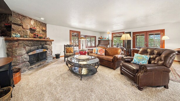 A cozy living room with a stone fireplace, leather sofa, and a coffee table. - Twin Fawns - EV #3417 (Estes Park)