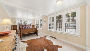 A room with a wooden bench, a cowhide rug, and large windows with a view of trees. - Twin Fawns - EV #3417 (Estes Park)
