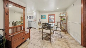 A dining area with a wooden bench, a round table, and chairs. There is a kitchen in the background with cabinets and a microwave. - Twin Fawns - EV #3417 (Estes Park)