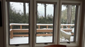 Drei Fenster mit Blick auf eine Holzdielen-Terrasse und verschneite Fläche.