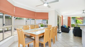 A spacious dining area with a large table and chairs, a ceiling fan, and large windows with curtains. - 2 Marto Court, Normanville (Normanville)