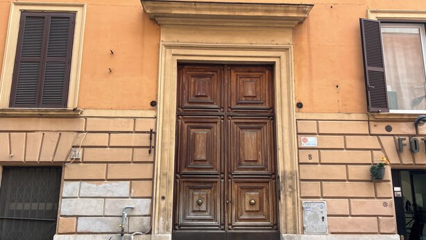 A traditional wooden door with a decorative lintel, flanked by two windows with shutters, set in a building with a stone base and a brick upper wall. - PAOLINA HOME IN ROME (Roma)