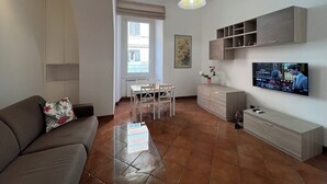 A modern living room with a sofa, TV, dining table, and a decorative vase. - PAOLINA HOME IN ROME (Roma)