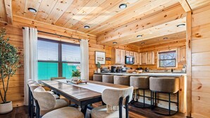 Una baita di legno con zona pranzo, cucina e bancone.