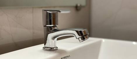 Ein weißes Waschbecken mit chromfarbenem Wasserhahn, auf dem der Markenname "SORONA" zu sehen ist.
