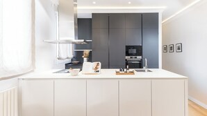 Et moderne køkken med en stor ø, integrerede hårde hvidevarer og et minimalistisk design.