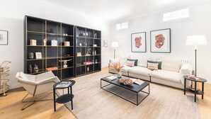 En moderne stue med sofa, sofabord og et sort bogreol.