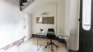 Et moderne kontor med et glasbord og en sort kontorstol, en hvid dør og en trappe med gelænder.