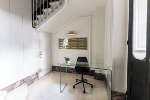A modern office space with a glass desk and black office chair, a white door, and a staircase with a decorative railing. - Columela II - Two Bedroom Apartment, Sleeps 4 (Madrid)