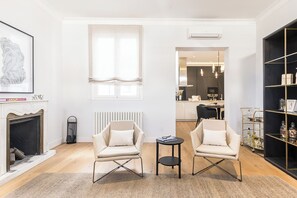Ein Wohnzimmer mit zwei Sesseln, einem kleinen Tisch, einem Kamin und einem Bücherregal.