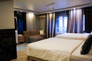 Hotellihuone, jossa on suuri sänky, sohva, työpöytä ja marmorilla koristeltu seinä.