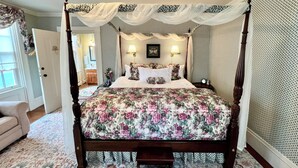 Una cama con dosel adornada con ropa de cama floral, un dosel y apliques de pared.