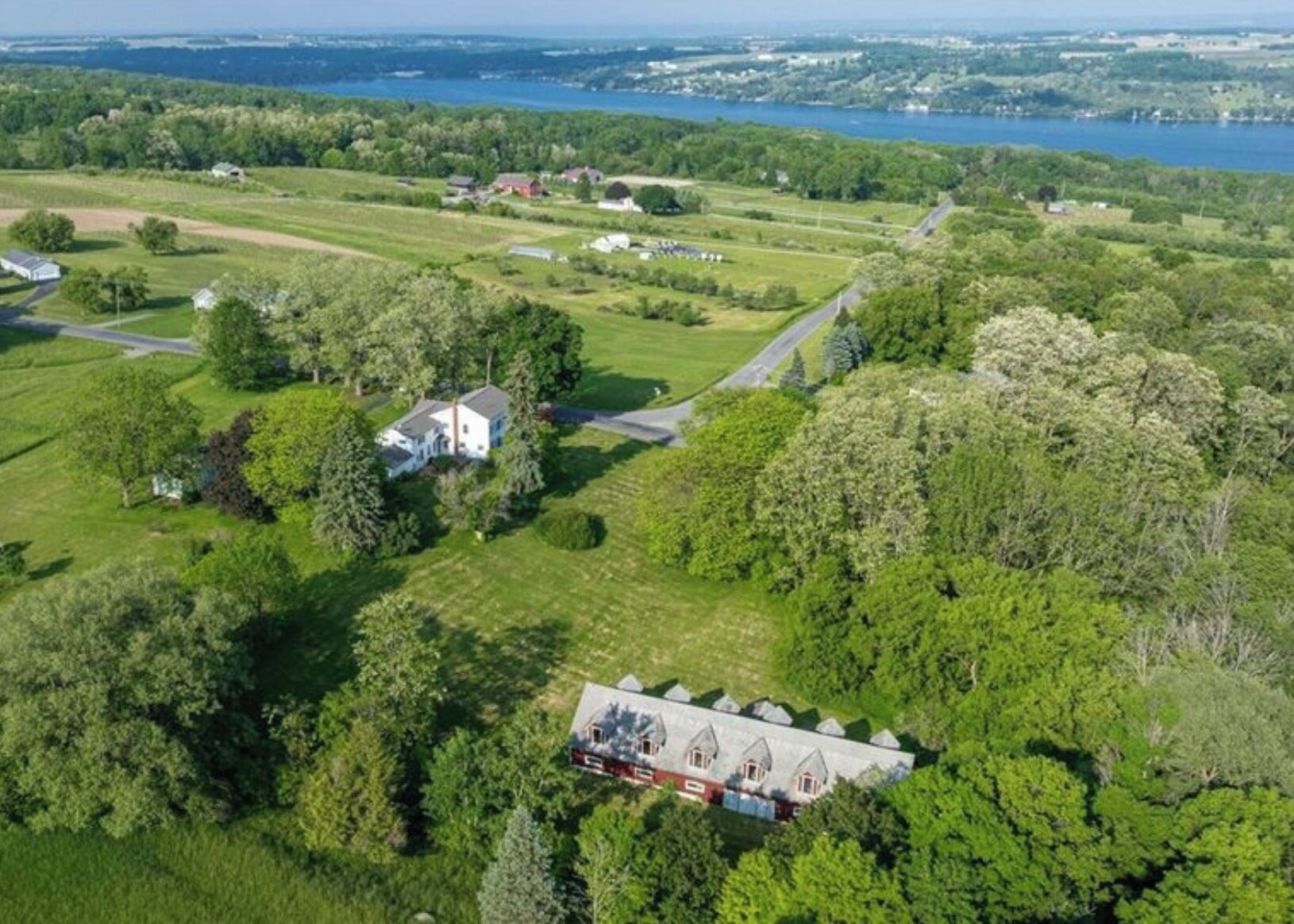 An aerial view of a rural property with a large house surrounded by lush greenery and fields.