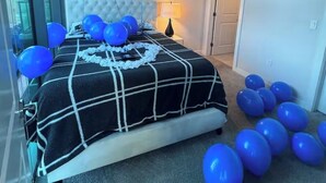 Une chambre à coucher avec un lit, un ventilateur de plafond et des ballons.