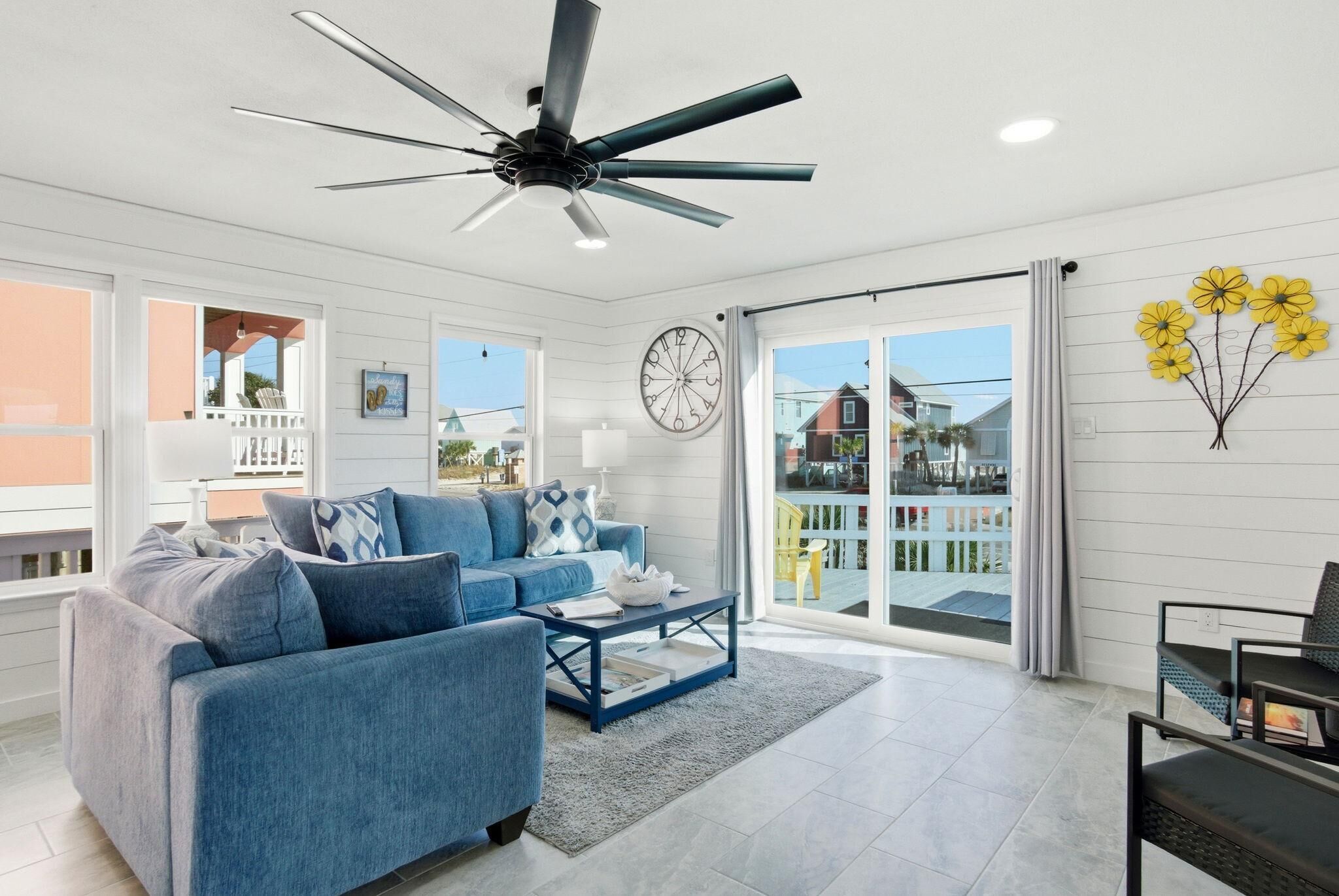 A spacious living room with a blue sofa, a coffee table, and a ceiling fan.