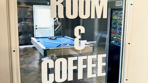 Une fenêtre sur laquelle on peut lire « SALLE DE LOISIRS ET CAFÉ », indiquant la présence d’une salle de loisirs et d’un bar à café.