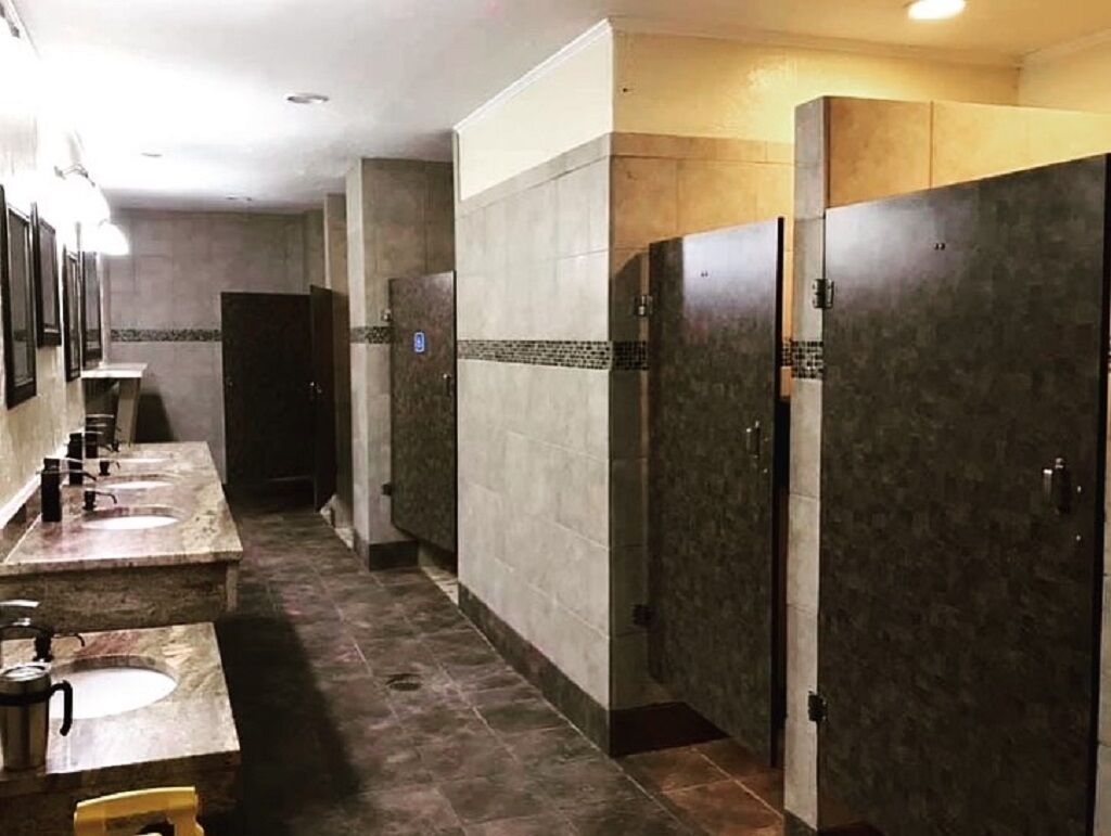 Des toilettes publiques dotées de plusieurs lavabos et de plusieurs cabines, avec des murs et un sol carrelés.