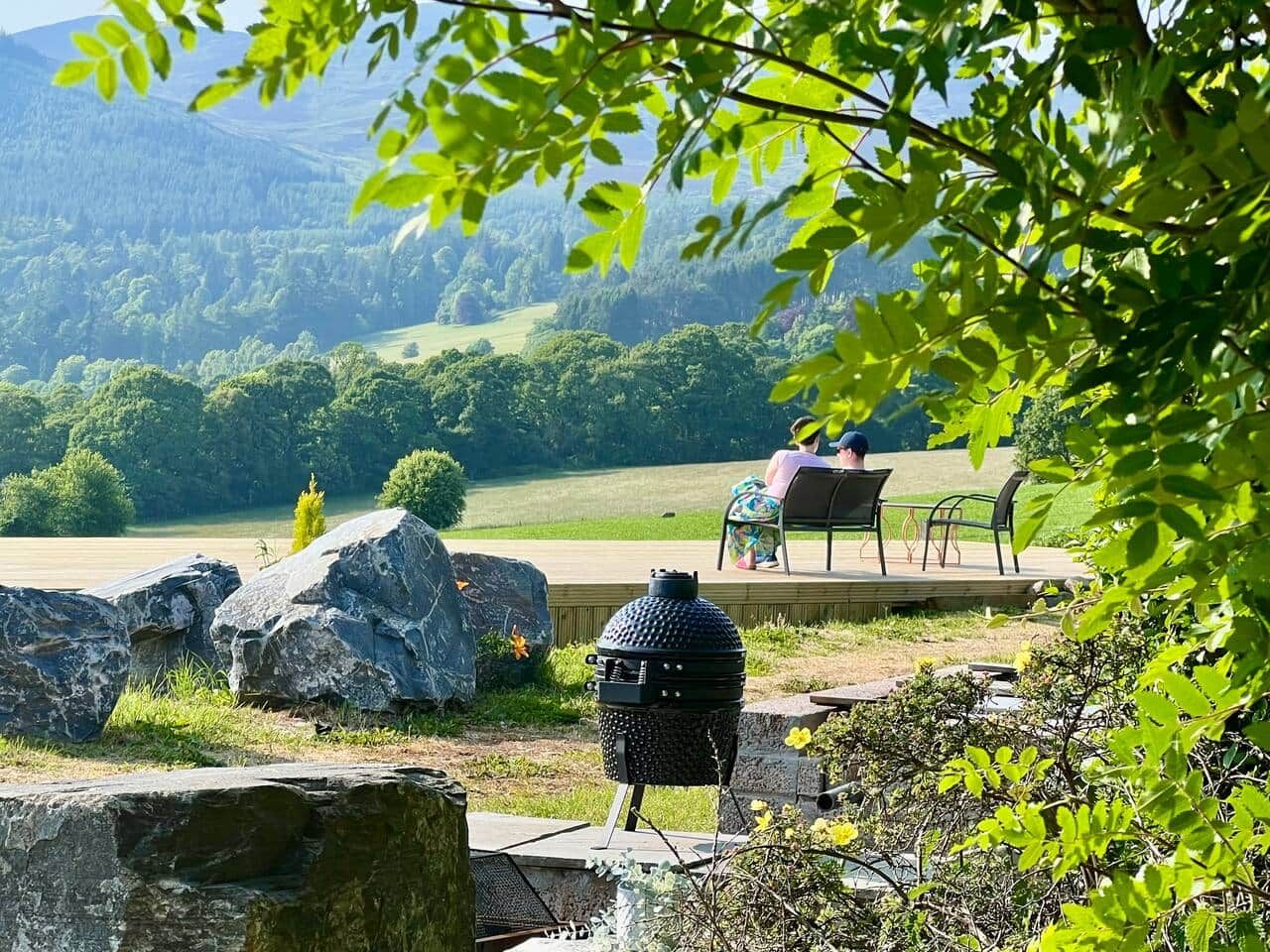 Una griglia per barbecue, posti a sedere all'aperto e vista su un paesaggio verde collinare.