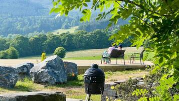 Una griglia per barbecue, posti a sedere all'aperto e vista su un paesaggio verde collinare.