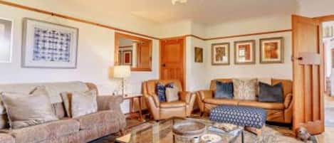 A living room with a sofa, armchairs, a coffee table, and a patterned rug.