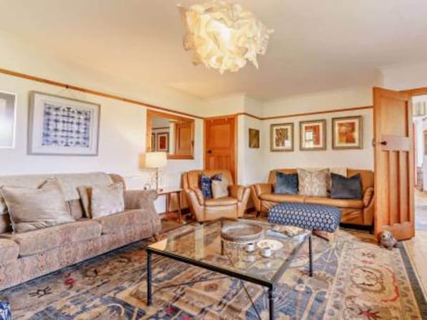 Un salón con sofá, sillones, una mesa de centro y un tapete estampado.