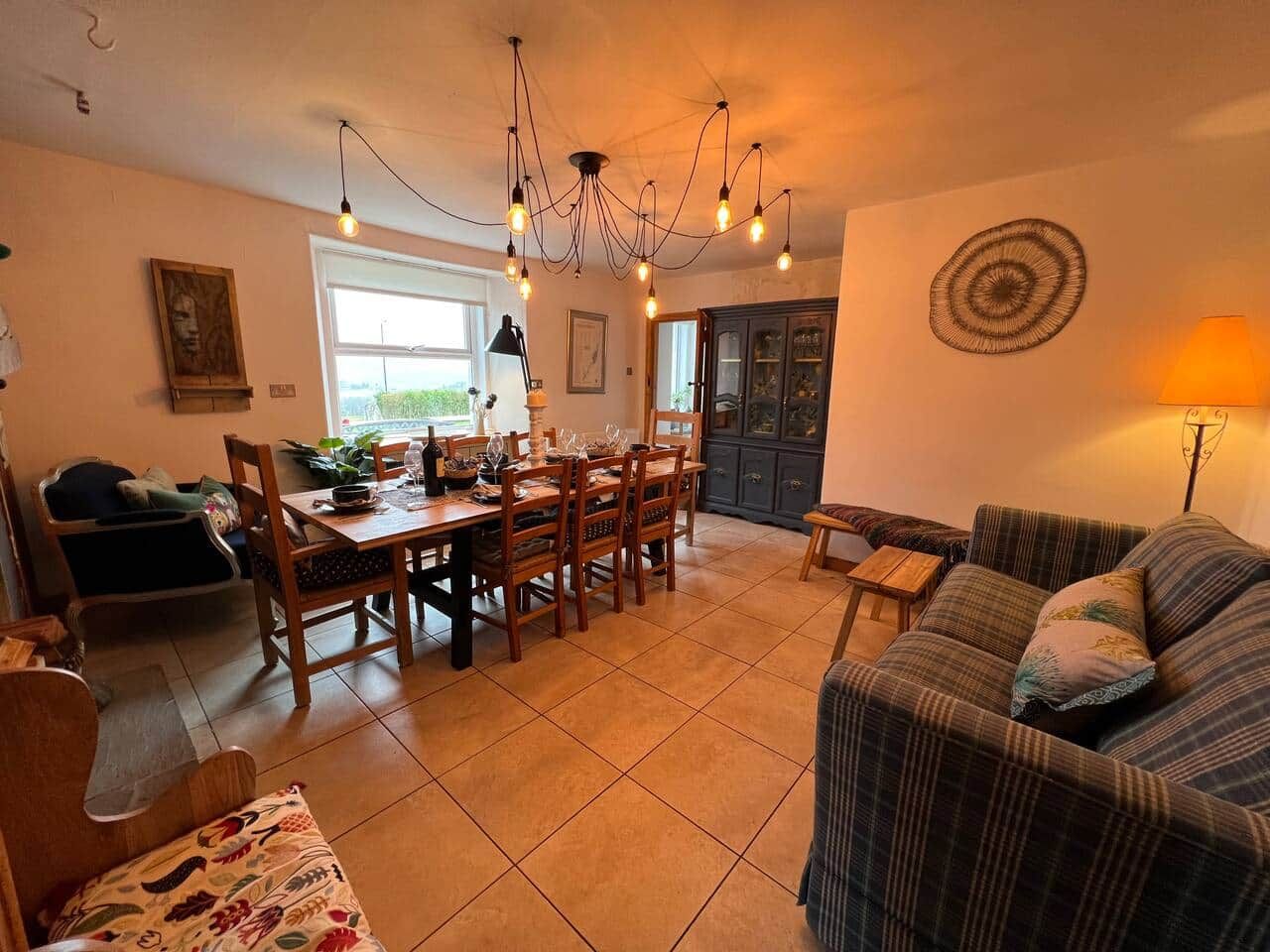 A dining area with a wooden table and chairs, a sofa, and a lamp.