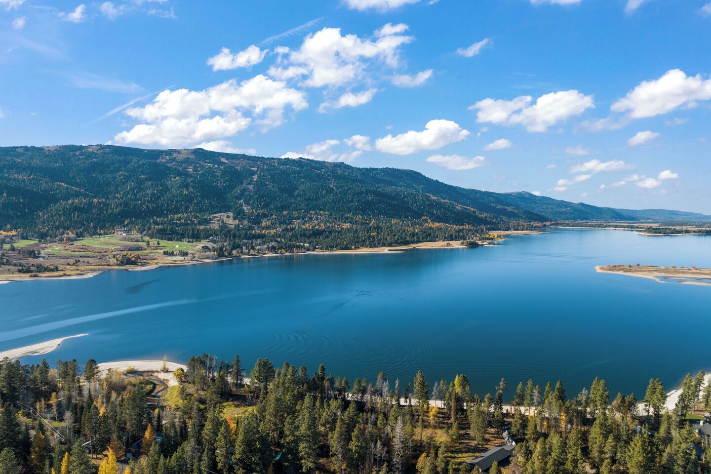 Una vista panorámica de un lago rodeado de colinas boscosas y un cielo despejado.