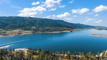 Una vista panorámica de un lago rodeado de colinas boscosas y un cielo despejado.