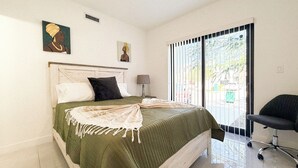 A bedroom with a bed, pillows, a nightstand, a lamp, and a chair. - Private Yoga Space & Cold Plunge Near Everglades (Florida City)