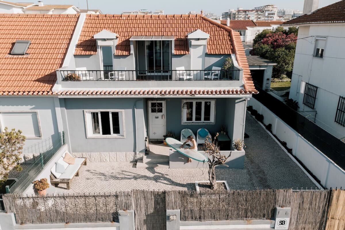 Una casa de dos pisos con techo de tejas, un balcón y un pequeño jardín.