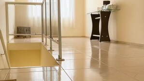 A spacious room with a tiled floor, a staircase with a handrail, and a small table with a coffee machine. - Apartment next to the Basilica of Saint Francis, Downtown Canindé, Ceará (Canindé)