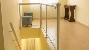 A staircase with a handrail, a small seating area, and a window with curtains. - Apartment next to the Basilica of Saint Francis, Downtown Canindé, Ceará (Canindé)