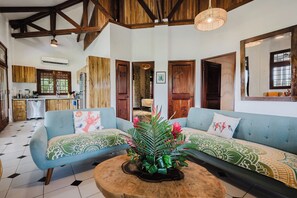 A spacious living area with a blue sofa set, a wooden coffee table, and a large mirror. - Casa Blue Wind • Private Home with Pool & A/C near Manuel Antonio Beaches (Quepos)