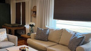 En stue med en beige sofa, stribede lænestole, et sofabord og en loftsvifte.