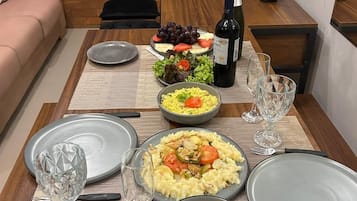 A dining table set with plates, bowls, and a bottle of wine, suggesting a meal setting.
