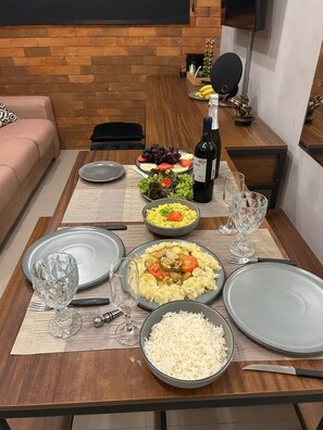 A dining table set with plates, bowls, and a bottle of wine, suggesting a meal setting. - 1003 Apto 2 Qtos João Pessoa Cabedelo (Cabedelo)