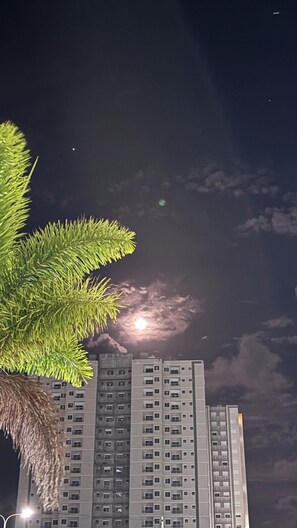 Un edificio alto con múltiples ventanas y balcones, bajo un cielo nocturno con luna y nubes.