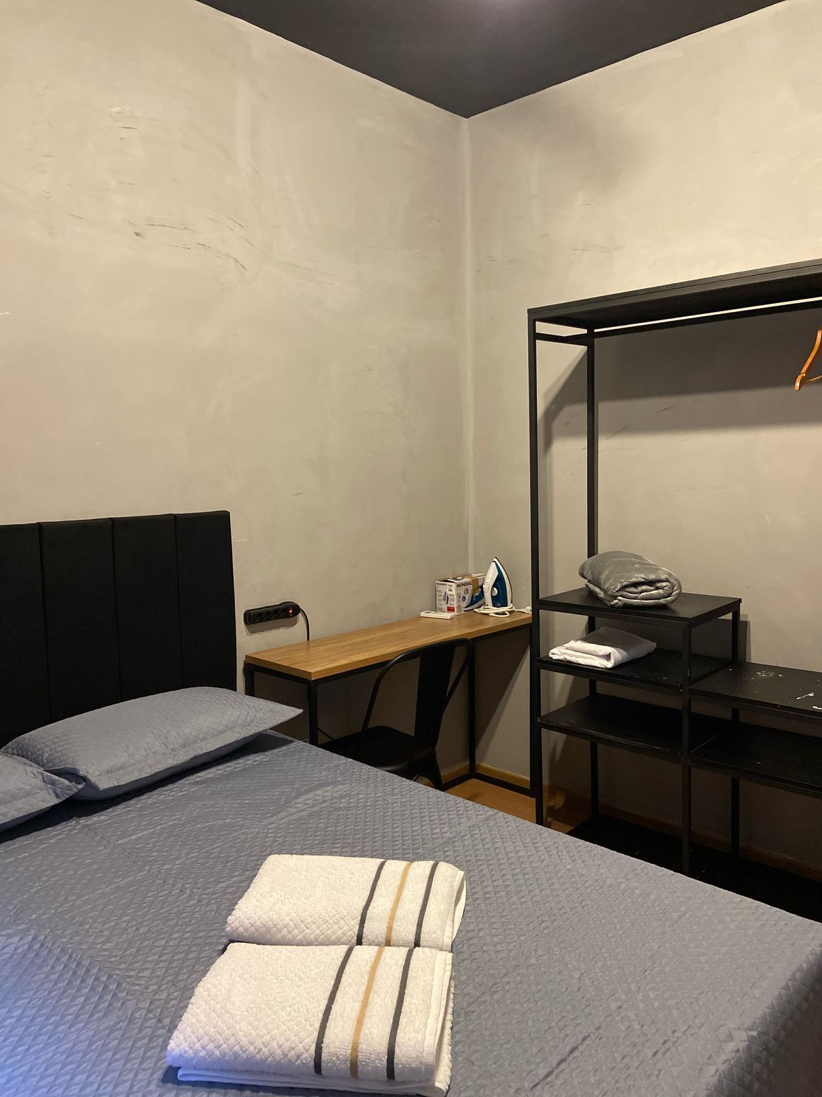 A compact hotel room with a bed, a desk, and a wardrobe.