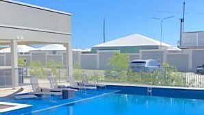 Ein Schwimmbecken mit klarem, blauem Wasser, umgeben von einem modernen Gebäude mit einer überdachten Terrasse.
