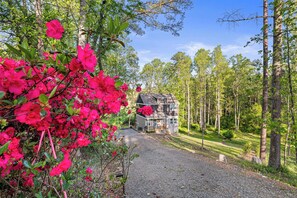 Ein Haus mit Kiesweg, umgeben von Bäumen und blühenden rosa Blumen.
