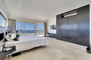 A modern hotel room with a large bed, a TV, and a wardrobe. - Sea Side Penthouse (kralendijk)