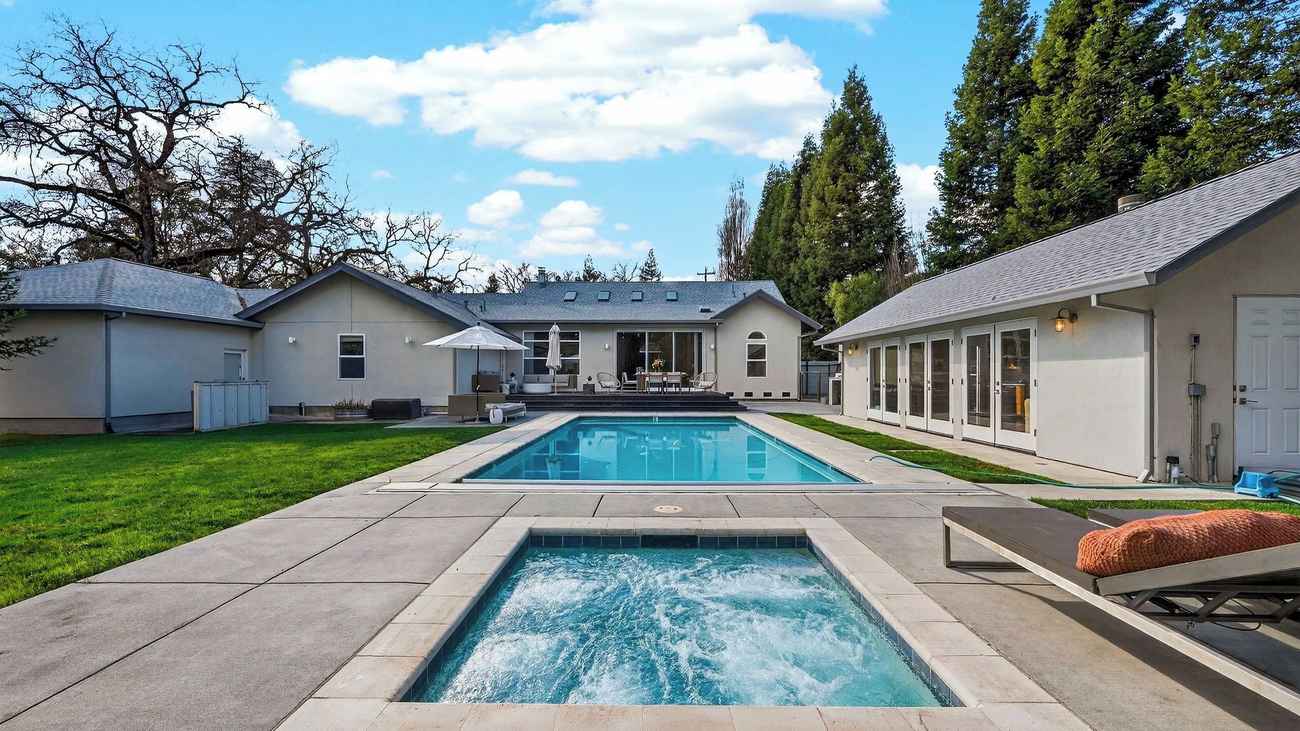 A residential property with a swimming pool, two attached houses, and a well-maintained lawn.