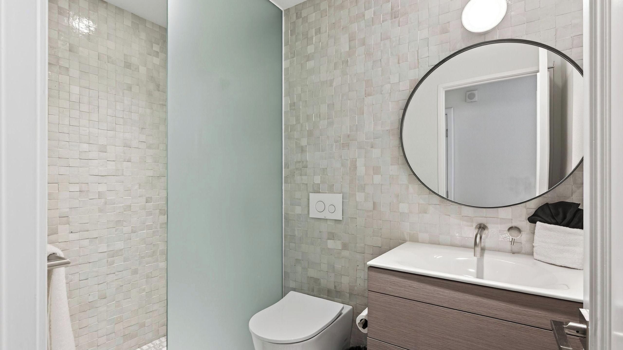 Une salle de bain moderne équipée de toilettes, d’un lavabo et d’un miroir.