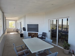 A balcony with a table and chairs, a grill, and a view of the city.