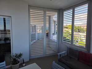 A room with a sliding glass door, a sofa, a small table, and a potted plant.