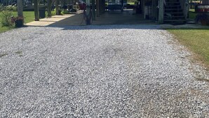 A covered outdoor area with a gravel path leading to a building with a metal roof. - Peaceful and Cozy 3 Bedroom house on the water in Bay St Louis! Sleeps 6. (Bay St. Louis)