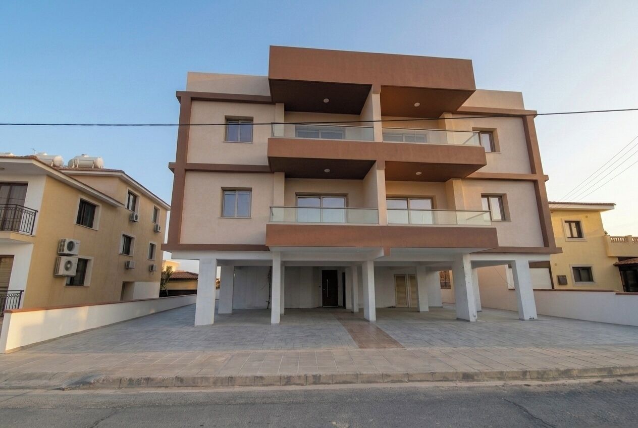 Un immeuble résidentiel à plusieurs étages, doté d’un toit plat, de balcons et d’un espace d’entrée abrité.