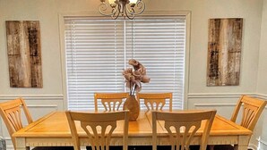 A dining room with a wooden table and chairs, a chandelier, and two wall-mounted paintings. - 5 min Walk to GWCC, Mercedes-Benz, World Cup! (Atlanta)