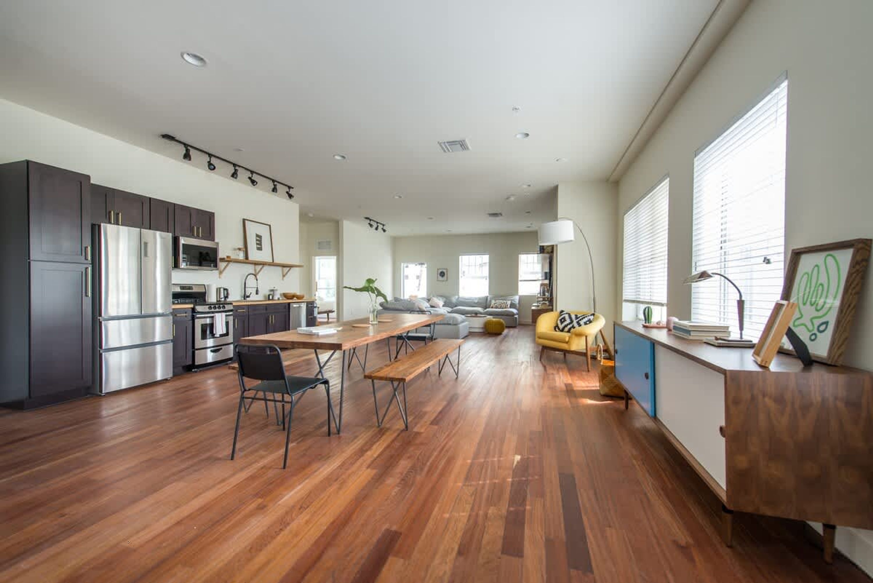A modern kitchen with dark cabinets, stainless steel appliances, and a wooden dining table.