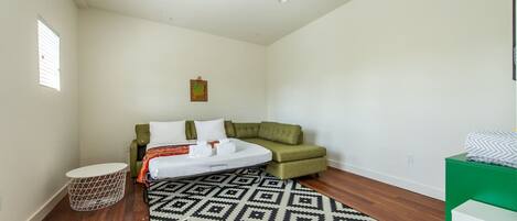 Ein Schlafzimmer mit einem Bett, einem grünen Sofa, einem gemusterten Teppich und einem kleinen runden Tisch.